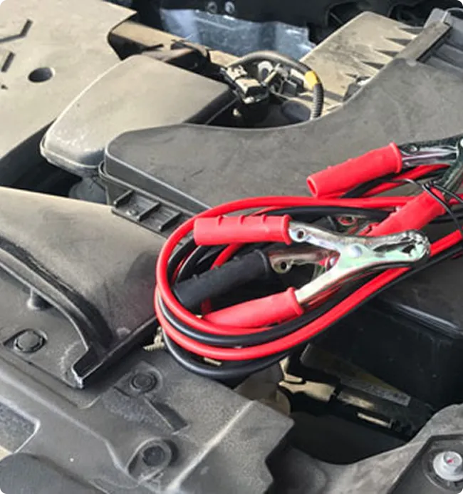 Red and black jumper cables resting on an engine